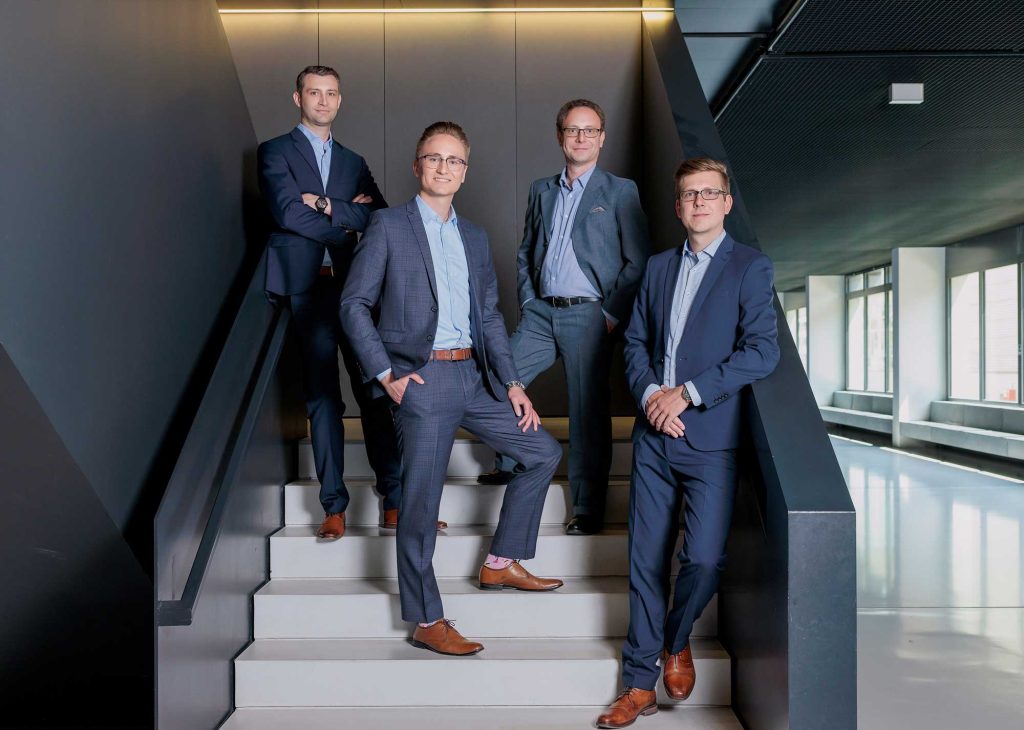 four person team of plasmotion GmbH standing on a staircase (équipe de quatre personnes de plasmotion GmbH debout sur un escalier)